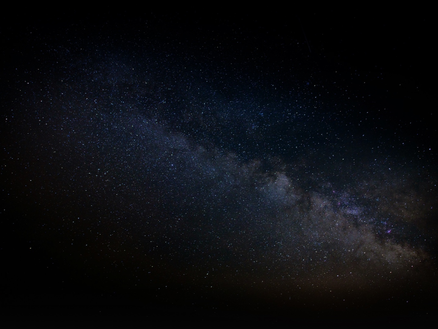 A wide view of the Milky Way galaxy stretching across a dark sky